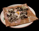 Galette complète garnie de jambon, œuf, champignons et persil. Une recette savoureuse pour un repas rapide.