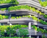 Edificio ecológico con balcones curvos cubiertos de exuberante vegetación verde, creando un oasis urbano.
