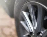 Primer plano de una llanta de aleación plateada, mostrando su diseño de radios y el neumático. La imagen sugiere movimiento y la importancia de la tracción delantera para el agarre en la carretera.