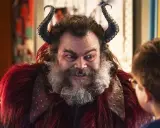 Jack Black med horn och rött päls, en karaktär från filmer med Jack Black, tittar på ett barn.