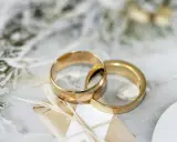 Due fedi dorate intrecciate su uno sfondo delicato. Pensare a cosa incidere sulle fedi è un passo importante per personalizzare questo simbolo d'amore.