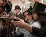 Una donna con un cappello piumato punta una pistola, protetta da un uomo con un cilindro. Un'altra donna con un cappello decorato sorride. Un momento intenso da "Dracula a love tale".