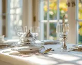 Une table dressée avec élégance, des verres et une théière en porcelaine. Le couteau est posé sur le verre, une astuce pour savoir comment poser les couverts après le repas.