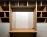 Einbauwand mit Schreibtisch und vielen Fächern. Weiße Schubladen bieten unsichtbaren Stauraum für Ordnung.