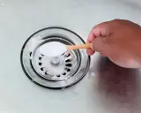 Maintenant, je vais aider à déboucher le siphon. Une cuillère de bicarbonate de soude est versée dans l'évier.