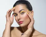 Mujer con un atrevido doble eyeliner amarillo y uñas a juego.