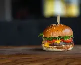 Apetyczny hamburger z serem, pomidorami i sałatą na drewnianym blacie.