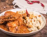 Gulasz z warzywami, podany z kremowym sosem i ozdobiony suszonymi papryczkami chili, kusi apetycznym wyglądem.