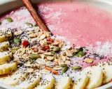 En rosa smoothie bowl med bananskivor, granola, pumpafrön, chiafrön och kokosflingor. En perfekt start på dagen!