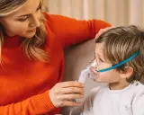 Mamma assiste il bambino con un inalatore per alleviare il broncospasmo.