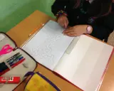 Bambina disegna un motivo geometrico su un quaderno di matematica. Matite, forbici e righello a portata di mano.