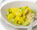 Un plat de tajine poulet citron, parfumé et coloré, servi avec du couscous et des olives vertes.