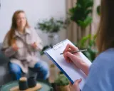 Psycholog notuje podczas sesji. Zastanawiasz się, ile zarabia psycholog policyjny?