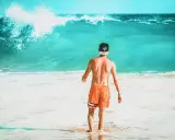 Chłopak w pomarańczowych spodenkach i czapce z daszkiem wchodzi do oceanu. Zastanawia się, ile się leci na Wyspy Zielonego Przylądka, by poczuć ten spokój.