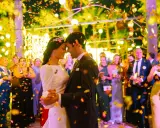 Novios bailando bajo confeti dorado. Invitados sonríen y celebran. ¡Ideas para bodas divertidas!