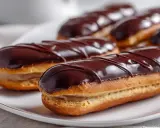 Des éclairs au chocolat, parfaits pour une recette gourmande. La crème pâtissière est généreuse, le glaçage brillant et les lignes de chocolat noir ajoutent une touche d'élégance.