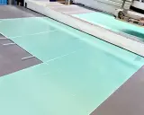 Große, hellgrüne Platten aus PVC-Schaum werden in einer Produktionsanlage zugeschnitten.