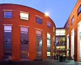 Nowoczesny budynek uniwersytetu SWPS Poznań z cegły, z dużymi oknami, oświetlony wieczorem.
