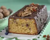 Pyszna babka orzechowa z polewą czekoladową, ozdobiona orzechami i rodzynkami, prezentuje się apetycznie na talerzyku.