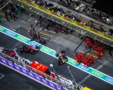 Equipos de F1 en boxes. Un coche Red Bull con un undercut f1 se detiene, mientras mecánicos de Ferrari se preparan.