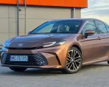 Brązowa Toyota Camry 2.5 Hybrid z eleganckimi felgami stoi na tle nowoczesnego budynku.