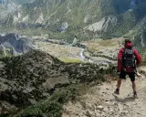 Widok z góry na dolinę i góry. Turysta z plecakiem zastanawia się, co zabrać w góry.