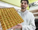 Mann hält eine große Blechschale mit Baklava, bereit für das Zuckerfest.