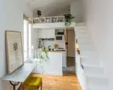 Un petit appartement optimisé avec un coin cuisine, un bureau escamotable et un escalier menant à une mezzanine. Idéal pour un **DIY rangement** créatif.
