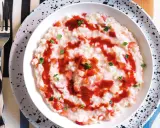 Un cremoso risotto alle fragole, guarnito con salsa di fragole e foglioline verdi, pronto per essere gustato.