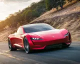 Roter Tesla Roadster rast auf einer Straße, die Beschleunigung von 0 auf 100 km/h ist atemberaubend.