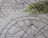 Kosmogram co to? Na papierze widnieją skomplikowane wykresy astrologiczne, pełne symboli planet i znaków zodiaku, przypominające mapę nieba.