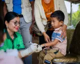 En sjukvårdare med handskar markerar ett barns finger efter vaccination i Kambodja.