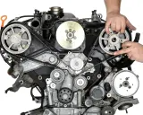 Mechanik wykonuje wymianę paska rozrządu w silniku samochodowym, precyzyjnie manipulując elementami układu.