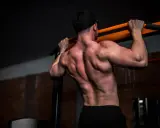 Mann mit starkem Rücken beim Klimmzug. Ziel: Muskelaufbau ohne Fett.