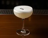 En elegant Pisco Sour med skummig topp och tre små prickar. Perfekt för ett pisco sour recept.