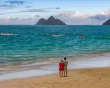 Para młoda na plaży podziwia wioślarzy na oceanie. Idealne miejsce na podróż poślubną.