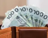 Pieniądze z wesela na konto: stos banknotów po 100 zł w brązowym portfelu.