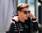 George Russell ajustándose la chaqueta, con gafas de sol y el logo de Mercedes.