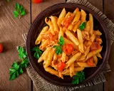 Penne z kurczakiem i pomidorami, udekorowane natką pietruszki. Idealne pytanie: co dzisiaj ugotować na obiad?