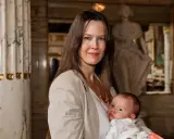 Elin Klinga med sitt barn. En vacker mamma med sitt nyfödda barn i famnen, omgivna av klassisk arkitektur.