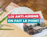 Un magazine sur la **loi Airbnb** est posé sur un meuble en bois. Le titre "Loi anti-Airbnb, on fait le point" est bien visible.