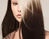 Mujer con cabello oscuro y mechones rubios claros, un estilo de **reverse balayage** que resalta su rostro.