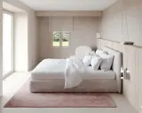 Chambre épurée avec lit blanc, tapis rose poudré et bois clair. Une belle inspi déco chambre pour un cocon de douceur.