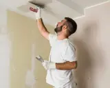 Hombre aplica mortero sobre techo pintado. Se puede aplicar mortero sobre pintura para reparaciones.