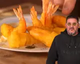 Un hombre sonriente muestra un plato de gambas a la gabardina doradas y crujientes, listas para disfrutar.