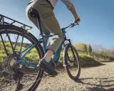 Fahrer auf einem blauen E-Bike mit Shimano Linkglide Schaltung genießt eine Fahrt auf einem Feldweg.