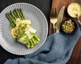 Une belle recette d'asperges vertes, nappées d'une sauce crémeuse et garnies de pistaches concassées. Un délice visuel et gustatif.