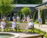 Seniorzy odpoczywają w pięknym ogrodzie przy sanatorium. Zastanawiasz się, ile kosztuje pobyt w sanatorium?