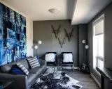 Canapé gris foncé, murs gris anthracite. Une grande toile abstraite bleue et blanche domine le salon moderne.