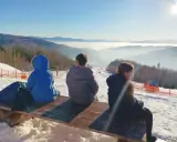 Dzieci siedzą na ławce, podziwiając widok na góra żar i dolinę spowitą mgłą.